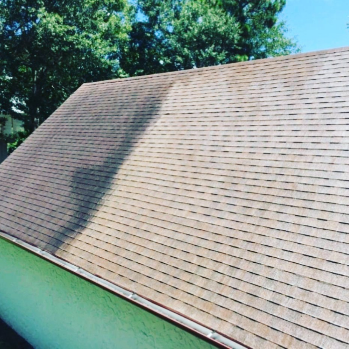 A roof that is half done being cleaned. One side is very dirty and the other looks like new.