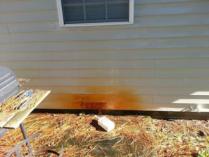 A photo of the side of a home that has extensive rust on it's siding panels.