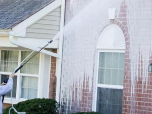 A photo of an Eight Five O employee cleaning the side of a brick structure using the softwashing method.